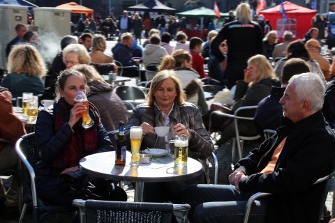 DreiPersonen sitzen auf dem Marktplatz und trinken ein Bier