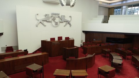 Ein großer Saal in der Bremischen Bürgerschaft mit Holzpult, rotem Teppich, Holztischen und roten Stühlen. 