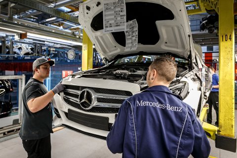 Zwei junge Männer bei der Montage eines weißen Mercedes: Produktion der C-Klasse im Mercedes-Benz Werk Bremen.