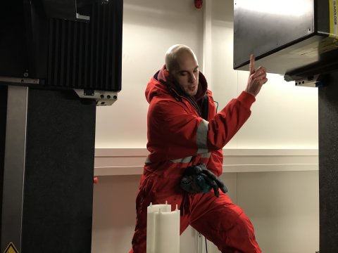 Ein Mann in rotem Overall steht zwischen zwei Röntgengeräten 