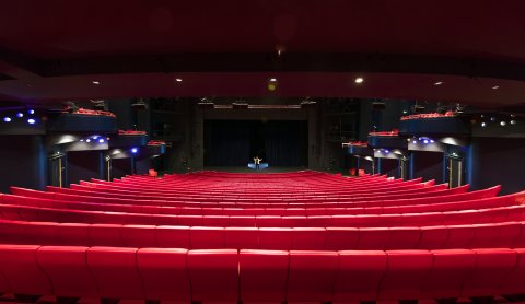 Ein großer Theatersaal mit roten Sitzreihen.