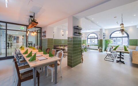 Innenräume des Restaurants "Plantenköök". Das Restaurant ist schlicht eingerichtet, mit grünen Fliesen an den Wänden und langen Tischen.