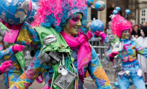 Eine mit Weltkugeln und bunten Farben geschmückte Frau zelebriert den Samba Karneval