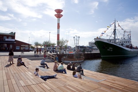 Schaufenster Fischereihafen in Bremerhaven: Menschen sitzen entspannt am Wasser.