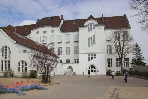 Weißes Gebäude des Schulmuseums mit Kindern davor.