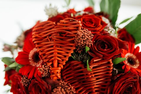 Zwischen roten Rosen stecken kleine Holzherzen.