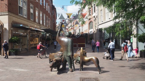 Zu sehen ist der Eingang zur Sögestraße, eine Einkaufstraße in Bremen. Eine Statue mit einem Mann und vielen kleinen Schweinen steht mittig im Bild.