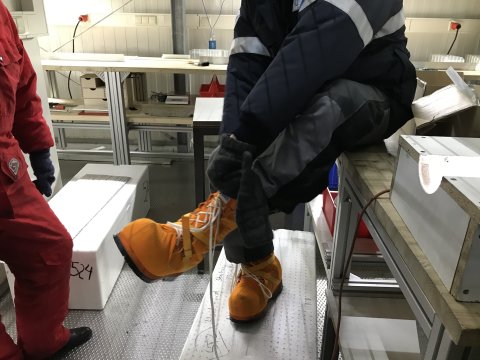 Ein Mann mit dicken gelben Schuhen und Winterbekleidung in einem Labor