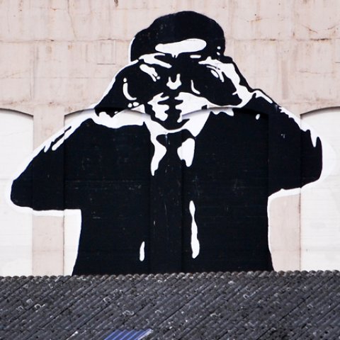 Huge Figure with binoculars on the facade of an old bunker.