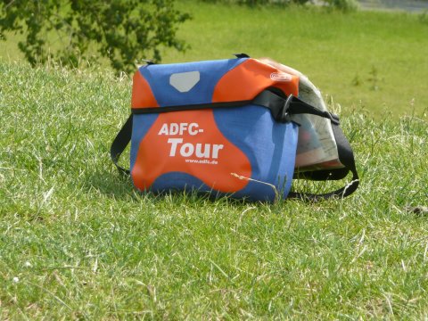 eine Umhängetasche vom ADFC steht auf einer Wiese. 