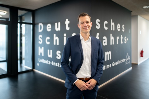 Mann im Anzug vor dem Schriftzug "Deutsches Schifffahrtsmuseum" 