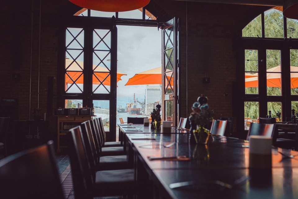 Blick aus dem Fenster eines Restaurants auf das Wasser und Schiffe.