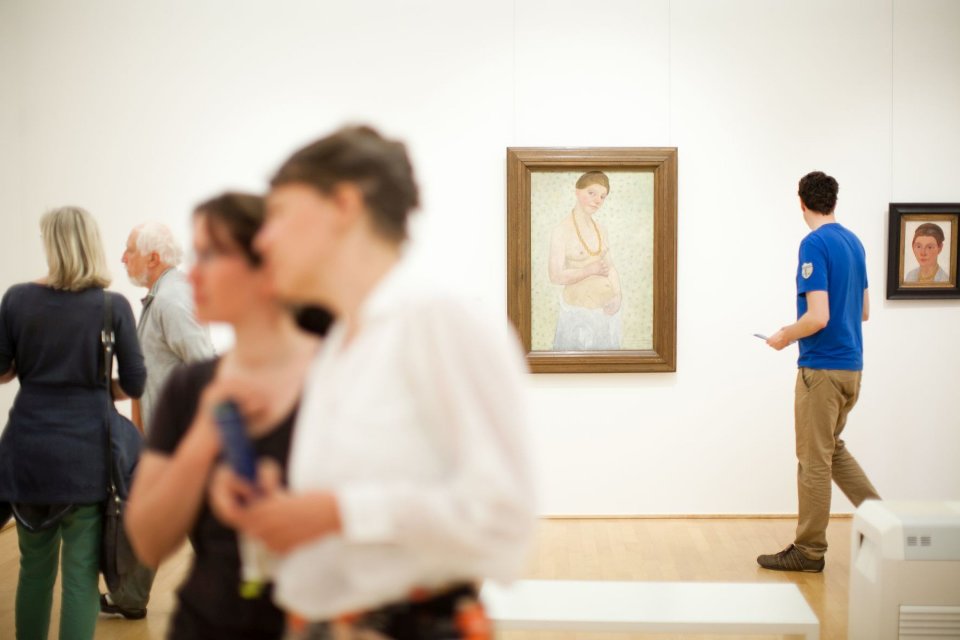 Besucher im Museum schauen sich Gemälde an.