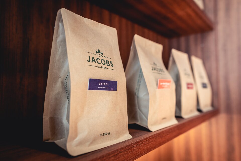 Vier Päckchen Kaffee stehen in einem Regal.