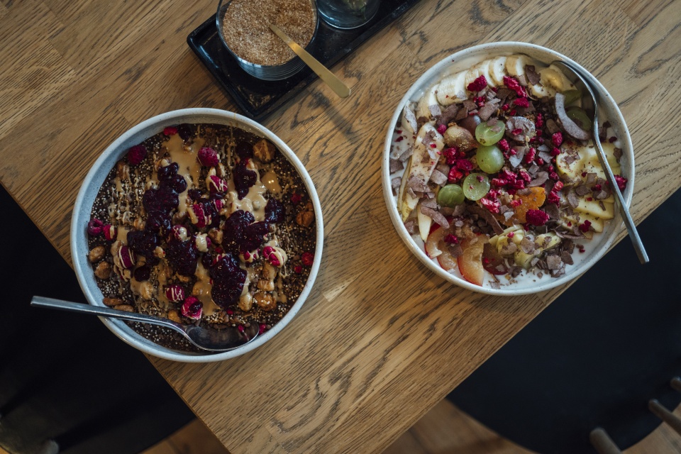 Zwei Schüsseln mit Müsli und Obst gefüllt stehen auf einem Tisch.