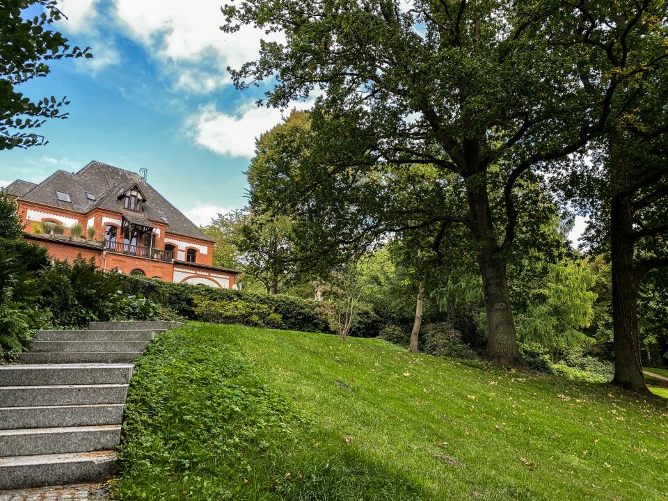 Eine Treppe führt durch einen Park. Im Hintergrund ist eine Villa zu sehen. 