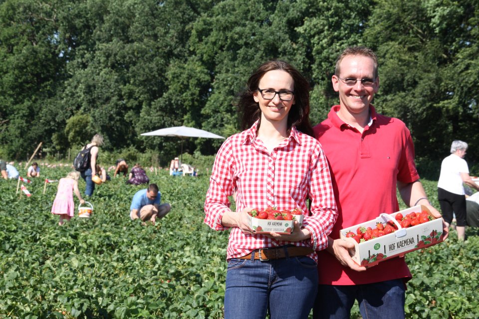 Man sieht Bea und Hajo Kaemena auf ihrem Erdbeerfeld. Beide halten ein Korb mit Erdbeeren