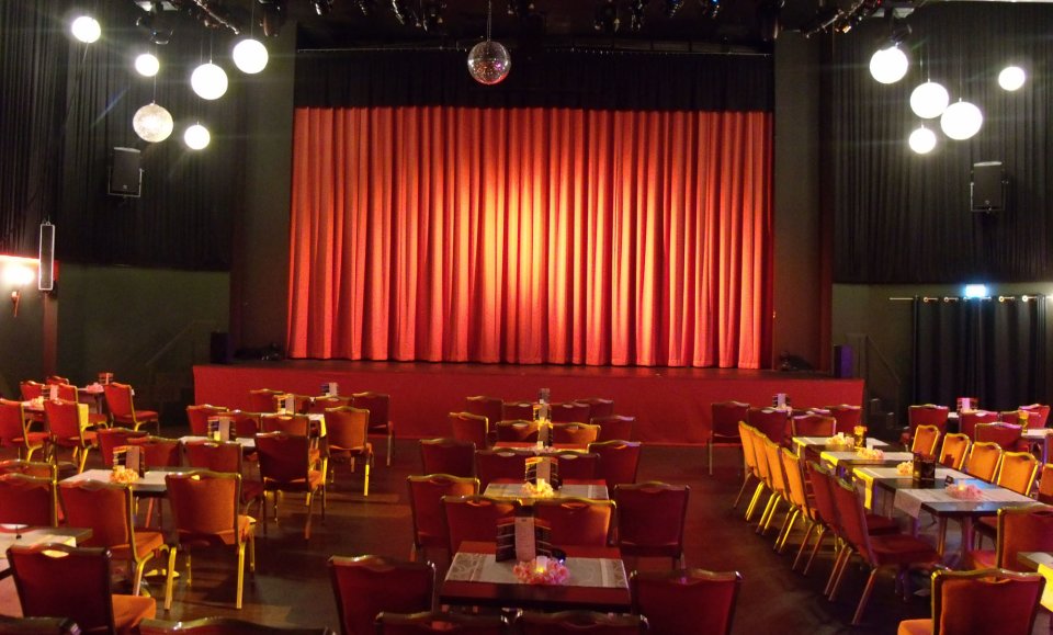 Der leere Theatersaal in schönem Licht und vor dem großen roten Vorhang.