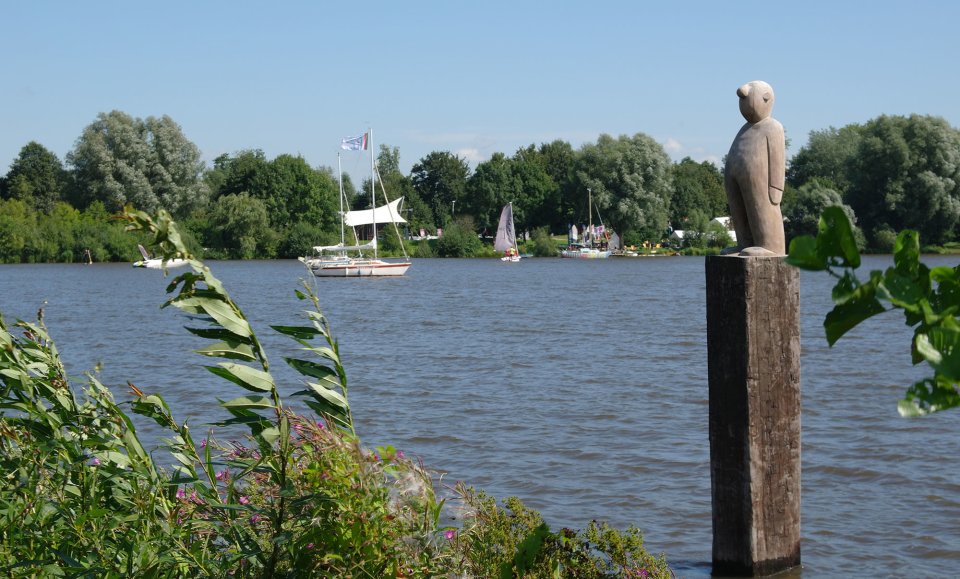 Ausblick auf den Vörder See mit der Skulptur Seemann im Vordergrund, im Hintergrund die Seebühne.