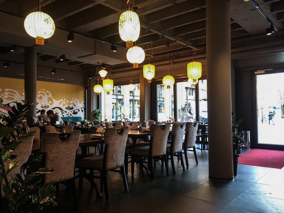 Das Restaurant Yakumi von innen. Man sieht mehrere Tische und asiatische Lampen.