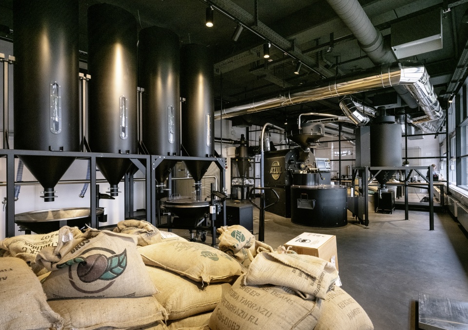Blick in die Azul Rösterei am Deich mit Kaffeesäcken im Vordergrund, im Hintergrund Geräte für den Röstvorgang