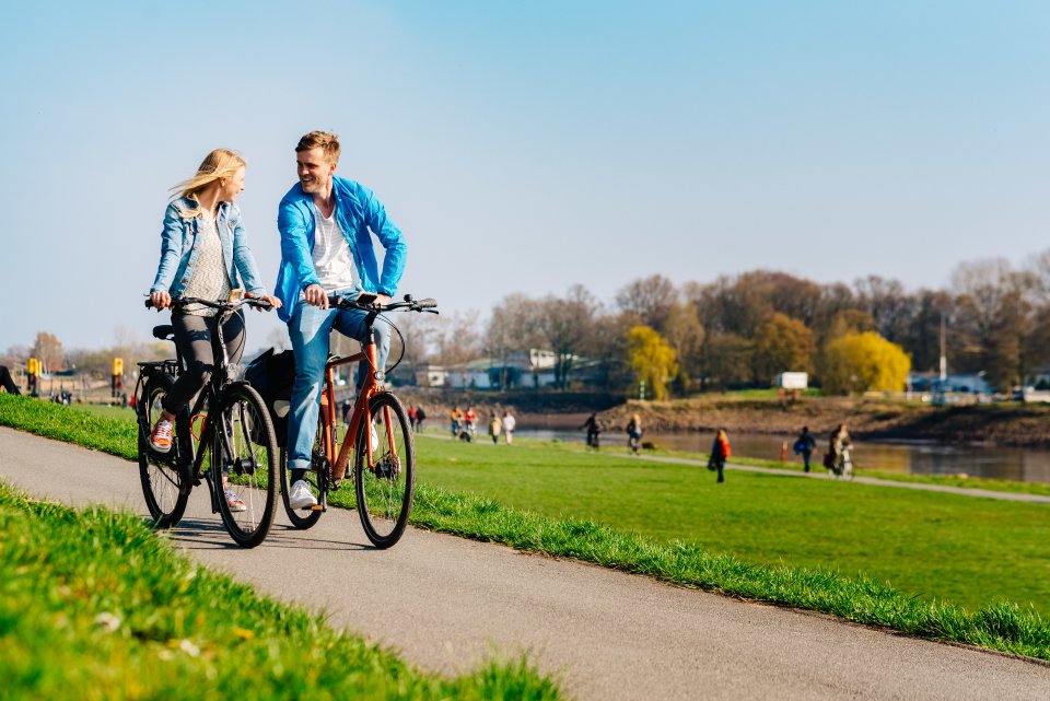 Ein junges Paar fährt Fahrrad am Deich
