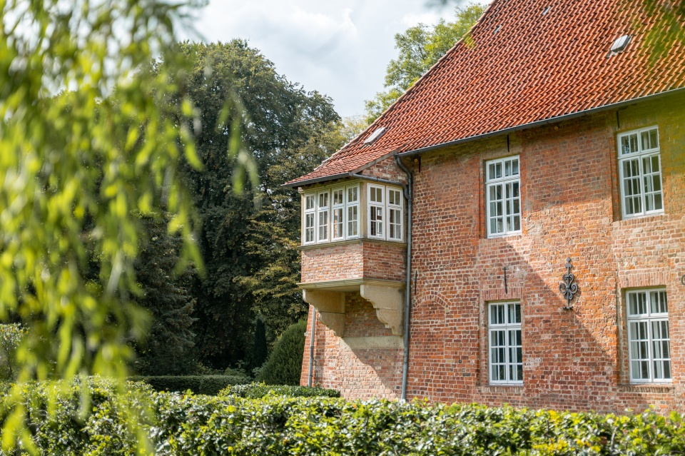 Seitenansicht der Burg Blomendal mit der Gartenvegetation.