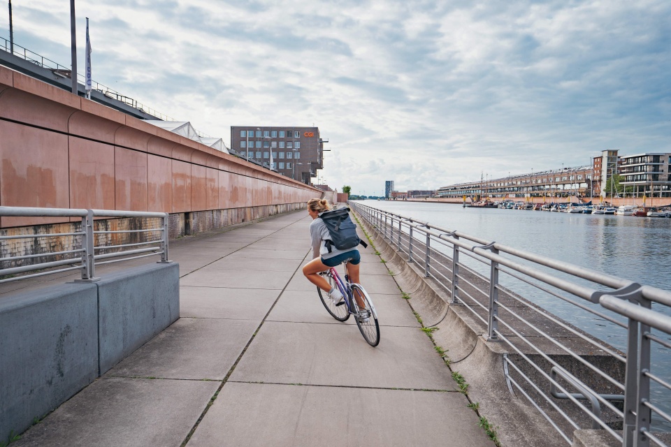 Eine Frau fährt mit einem Fahrrad an einer Promenade entlang.