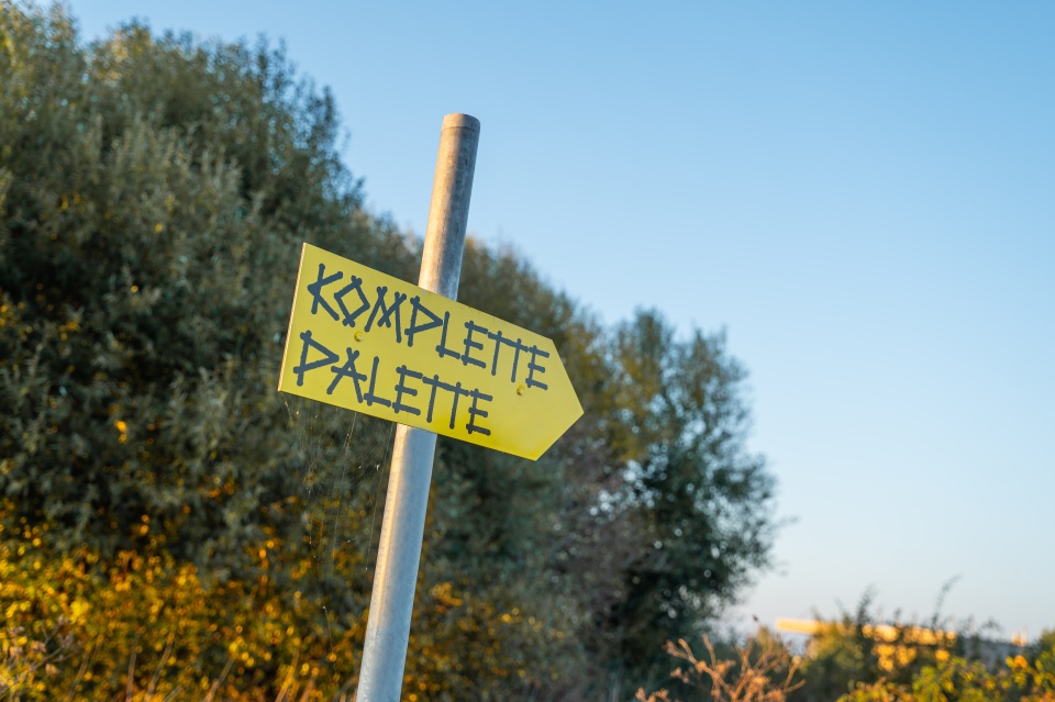 Gelbes Pfeil-Schild mit der Aufschrift: Komplette Palette