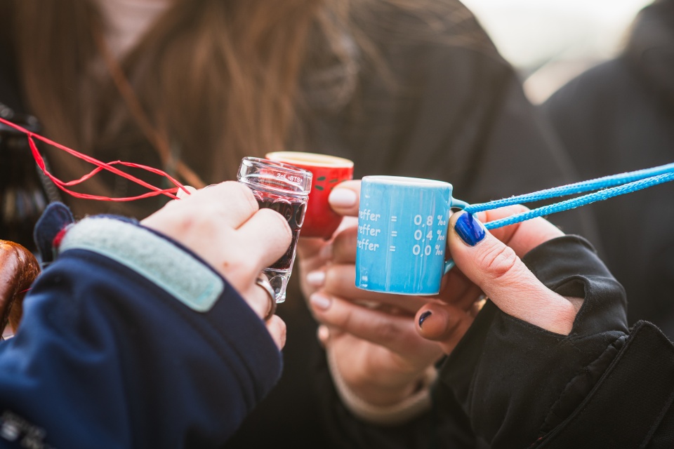 Drei Personen halten ein Schnapsglas in die Kamera.