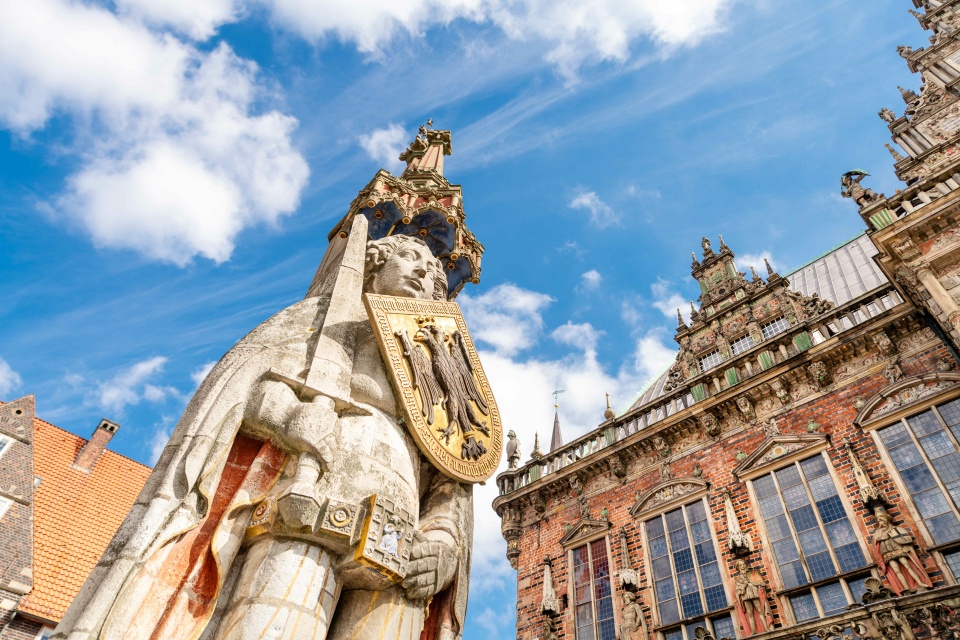 Zu sehen ist der Bremer Roland auf dem Marktplatz. Im Hintergrund ist das Rathaus zu sehen.