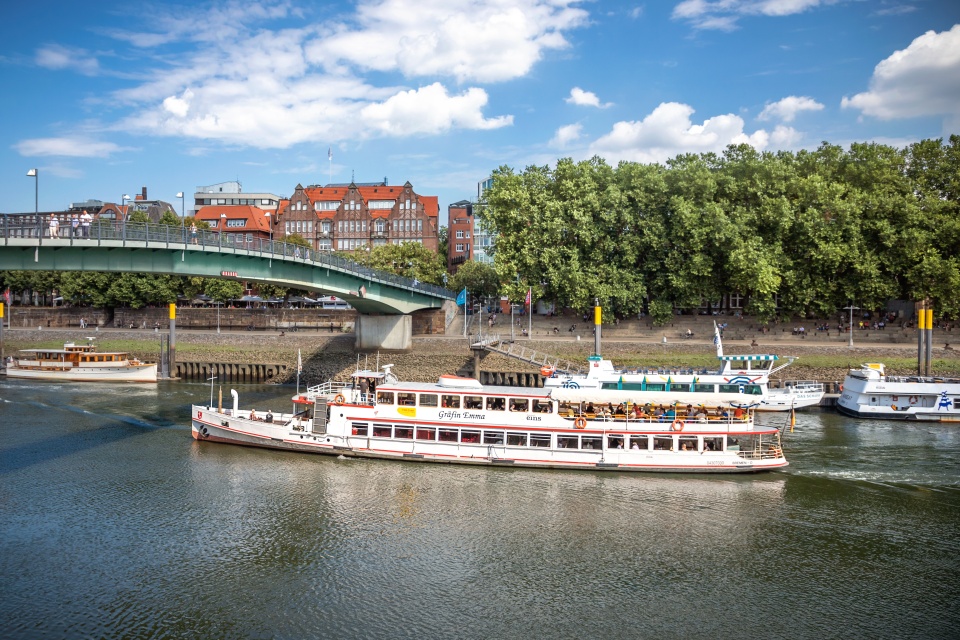 Ein Schiff fährt in der Weser bei einer Brücke. 