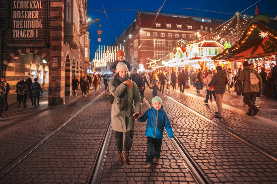 Eine Frau geht mit zwei Kindern auf dem Bremer Weihnachtsmarkt spazieren