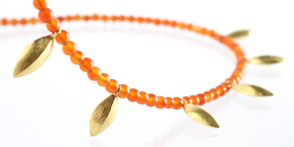 Eine Kette mit orangenen Perlen und goldenen Blättern.