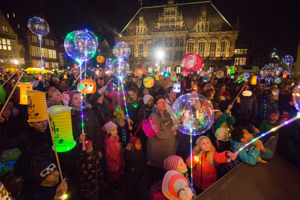 Laternenumzug am Abend: Zahlreiche Menschen stehen mit Laternen auf dem Bremer Marktplatz vor dem Rathaus. 