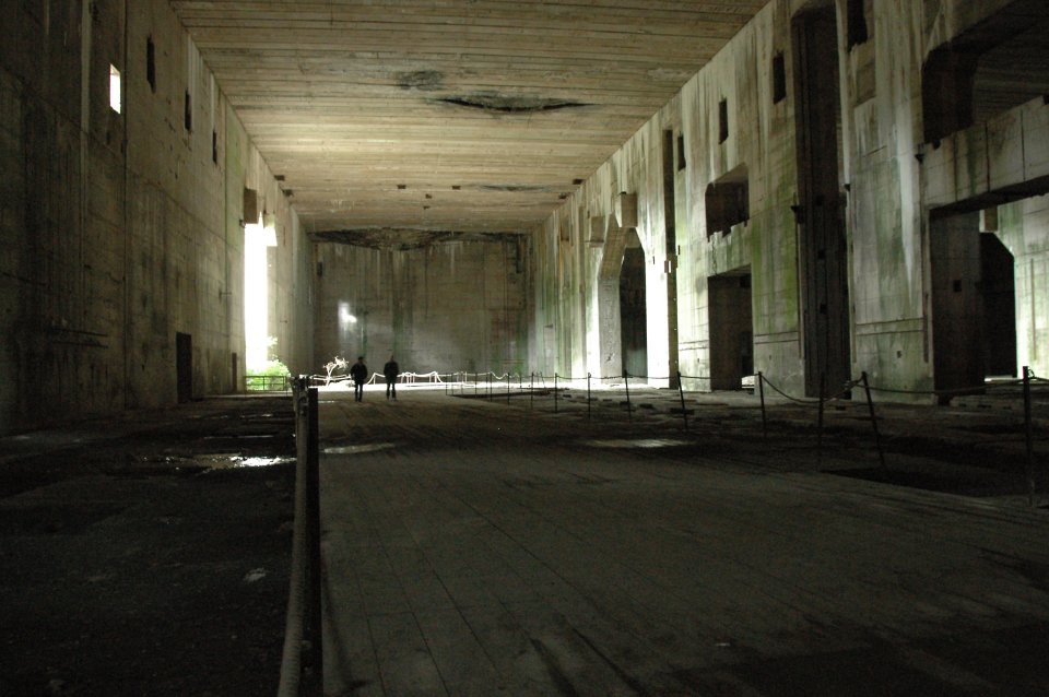 Die Ruine des riesigen Bunker Valentin von innen. Zwei Männer laufen durch das finstere Gebäude.