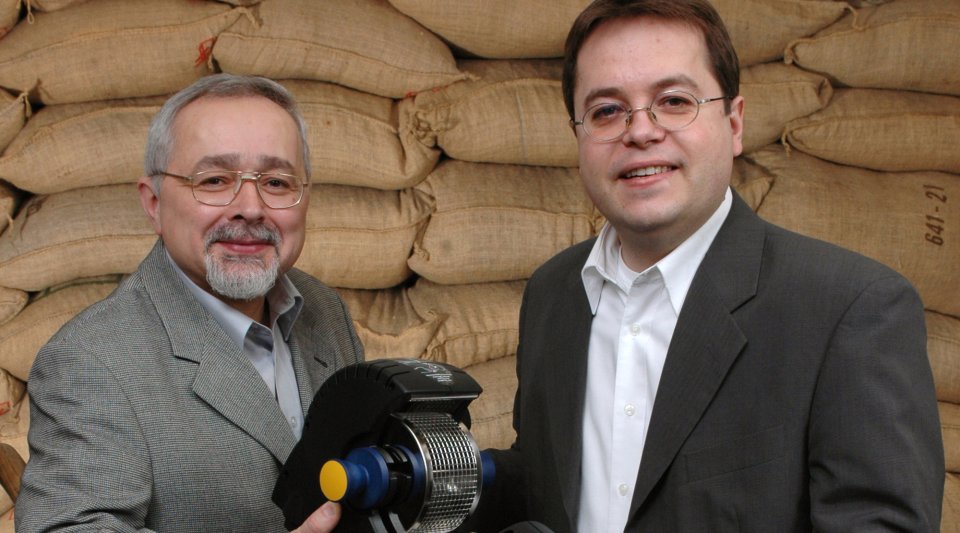Zwei Männer halten eine Kaffeemaschine