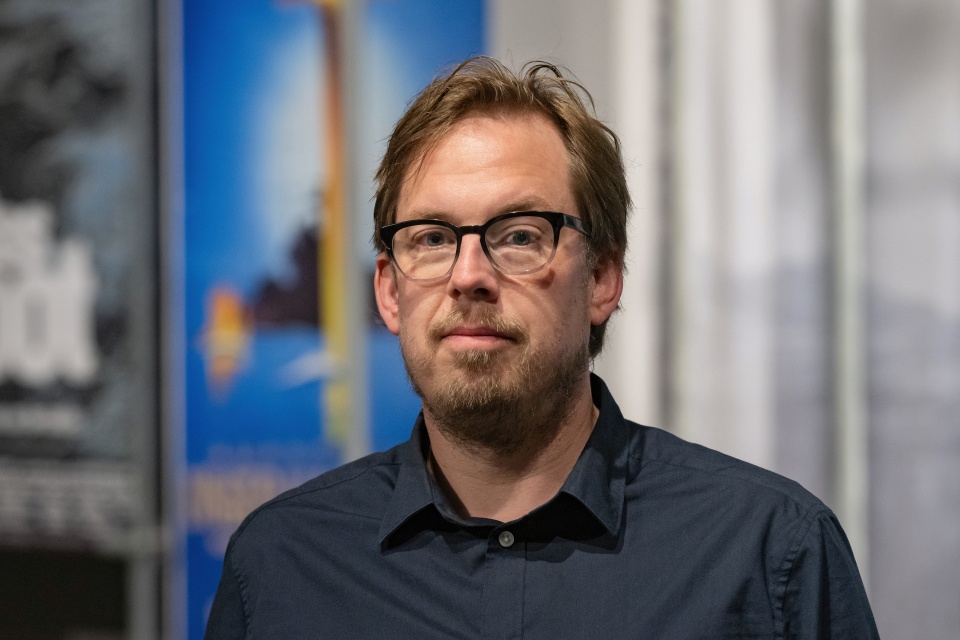 Ein Mann steht vor einem verschwommenen Hintergrund.