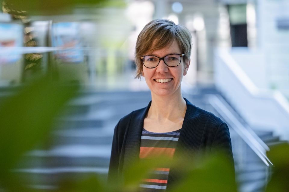 Portrait von einer Frau, die vor einer Treppe steht und lacht