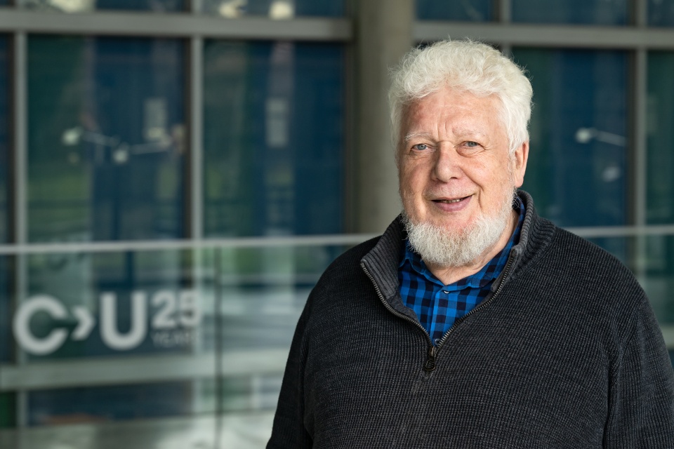 Klaus Boehnke steht im Freien vor einem Glasgebäude.