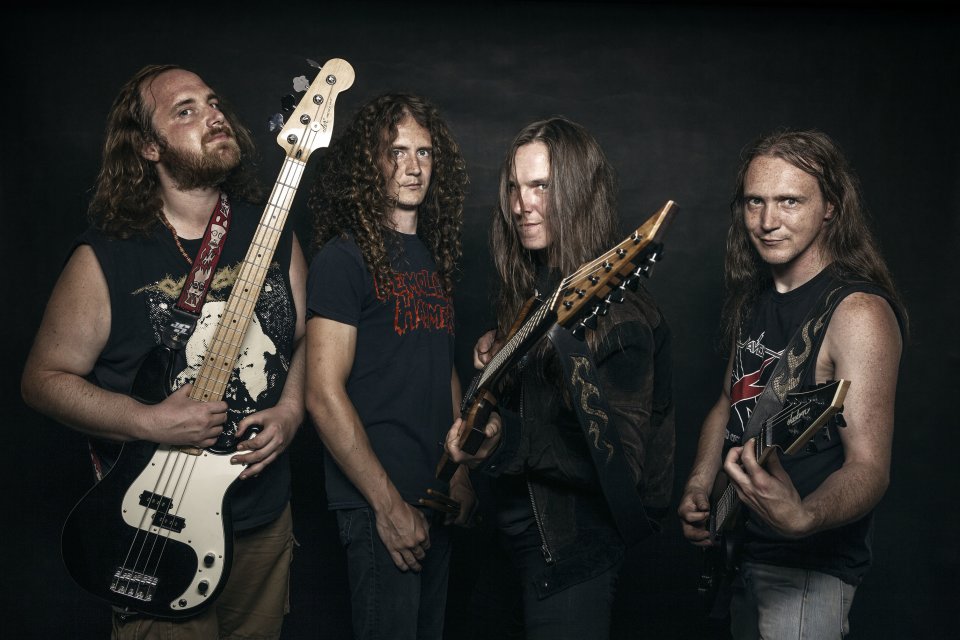 Die vier Bandmitglieder stehen vor einem schwarzen Hintergrund und halten ihre Gitarren ins Bild.