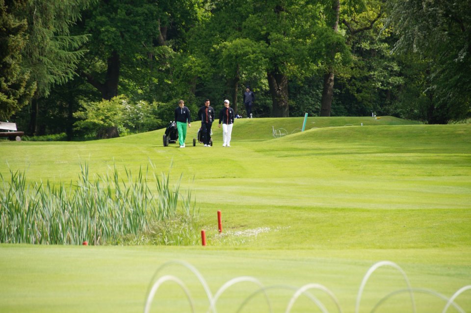 Drei Golfer ziehen ihre Taschen über die Anlage in Garlstedt