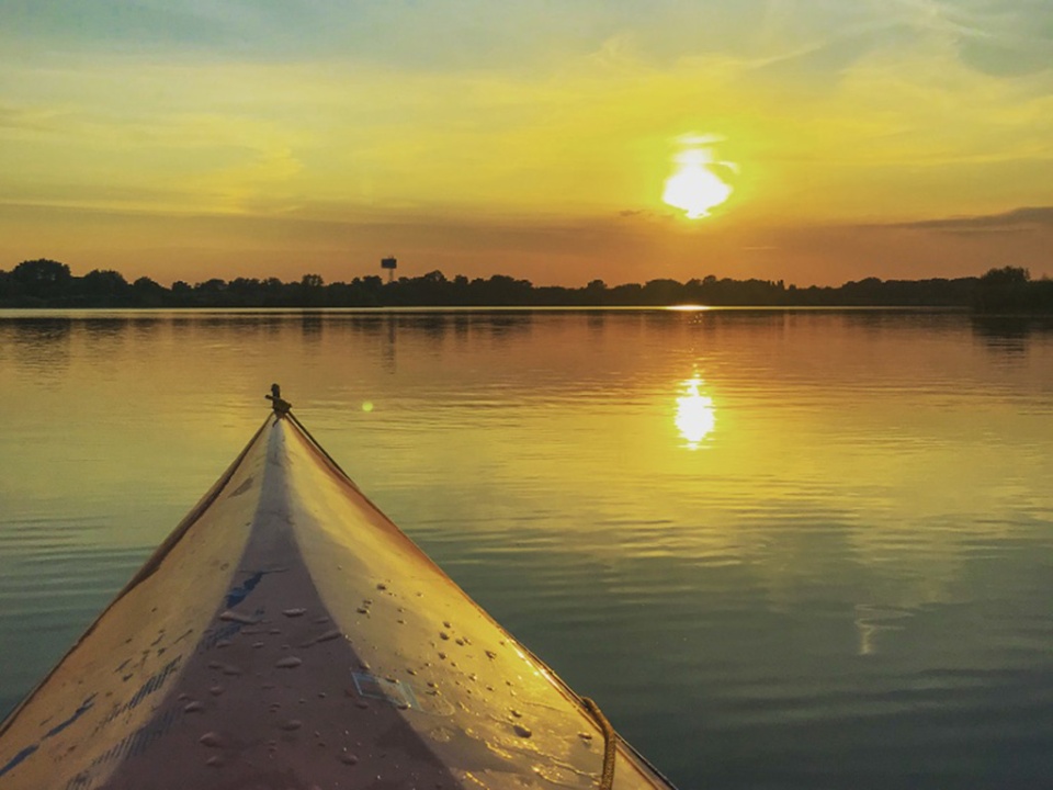 Das Frontteil eines Kanus auf dem Wasser, während des Sonnenuntergangs