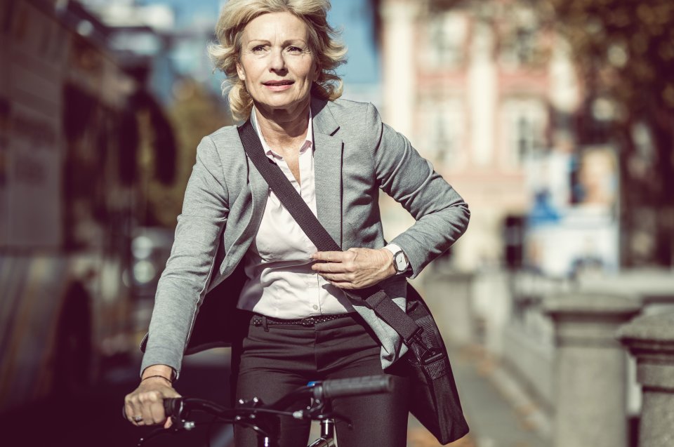 Frau sitzt im Anzug auf dem Fahrrad