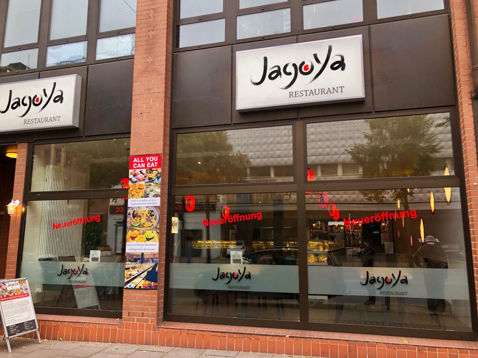 Das Sushi-Restaurant von außen. Es klebt ein Sticker an der Scheibe, auf dem "Neueröffnung" steht.