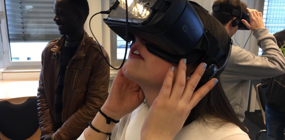 Ein Mädchen schaut vor weiteren Personen durch eine VR-Brille 