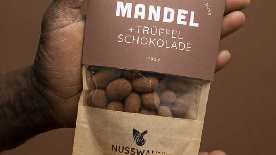 Eine Hand hält eine Verpackung mit Mandel und Trüffelschokolade von Nusswahn.