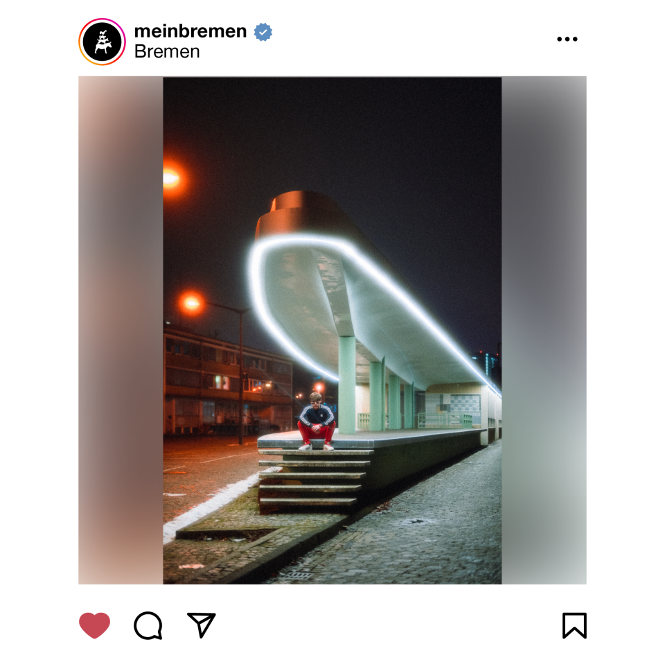 Das Foto zeigt das "Alte Zollamt " in der Bremer Überseestadt. Das Gebäude verfügt über Säulen, einer beleuchteten Überdachung und Treppenstufen. Auf den Stufen sitzt eine Person im Trainingsanzug und blickt in die Kamera.