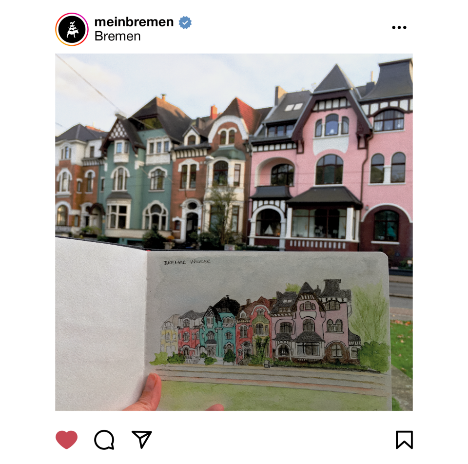 Eine Hand hält die Seite eines Skizzenbuches ins Foto, auf dem eine bunte Reihe Altbremer Häuser in Aquarell gemalt wurde. Im Hintergrund des Fotos ist die gleiche Häuserreihe zu erkennen, die als Vorbild für die Zeichnung diente.