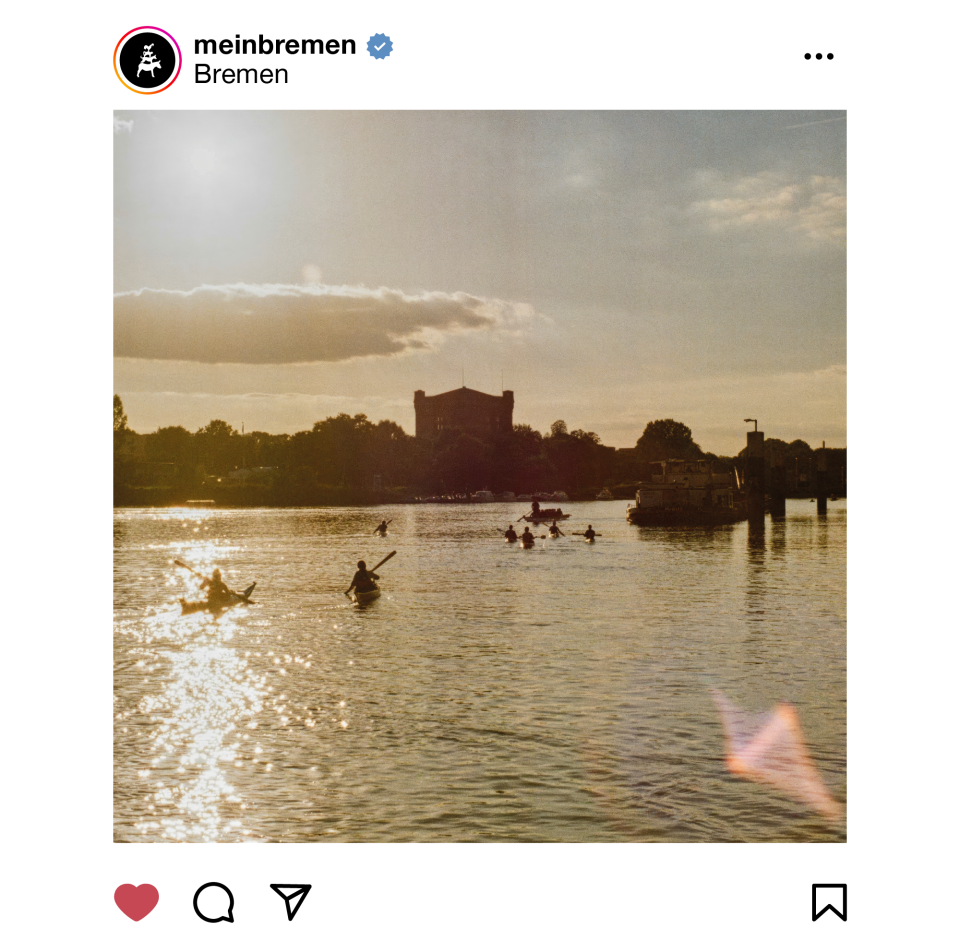 Das Foto zeigt die Bremer "Weser" und auf der anderen Uferseite die sogenannte "Umgedrehte Kommode" - ein quadratisches Gebäude. Ein paar Kanufahrer paddeln über die Weser - das Foto ist in einem analogen Stil gehalten.